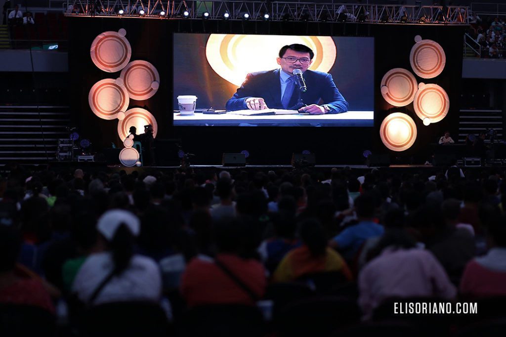 Bro. Daniel Razon as seen on the big screen of MOA Arena, assists Bro. Eli Soriano in hosting the program by reading verses in the Bible during the question-and-answer portion of the Worldwide Bible Exposition. (Rodel Acuvera Lumiares, Photoville International)